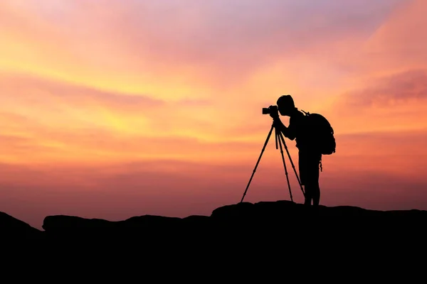Silueta del hombre fotografía y selfie con montaña al atardecer —  Fotos de Stock