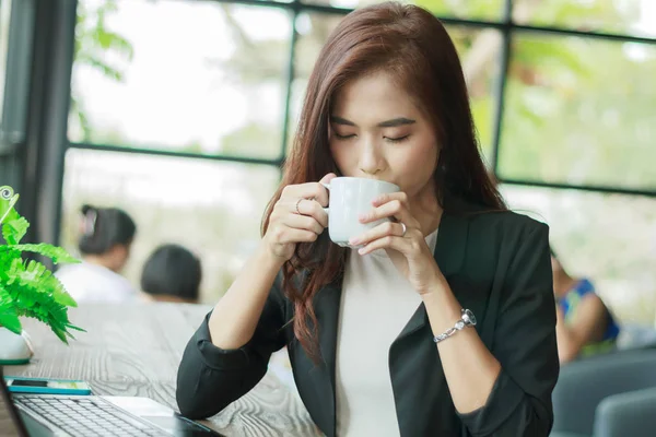 Asiatique femme d'affaires travaille et boit du café, soft focus — Photo