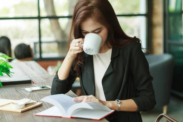 Asiática mujer de negocios está trabajando y bebiendo café y leyendo —  Fotos de Stock