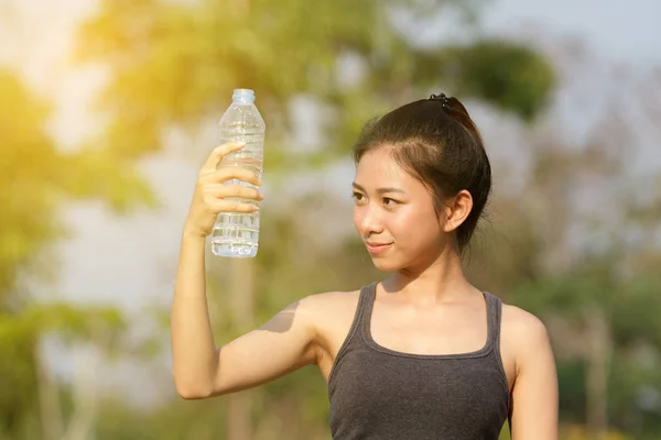 Femme sportive asie boire de l'eau en plein air le jour ensoleillé — Photo