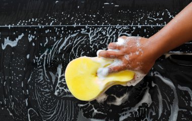 Adam sarı sünger ile köpük kullanarak araç yıkama .