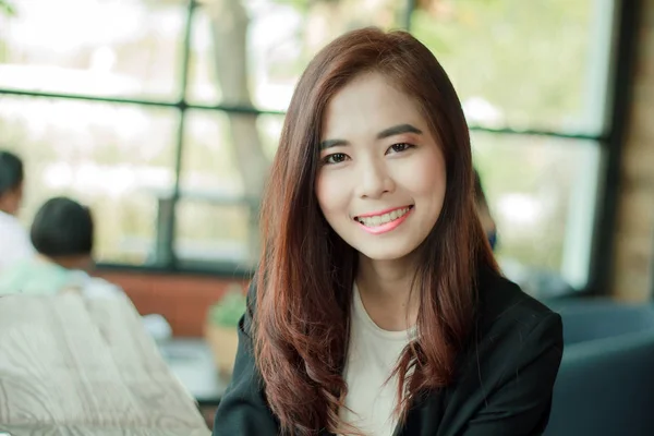 Asiática empresaria sonriendo mientras espera café en la cafetería —  Fotos de Stock