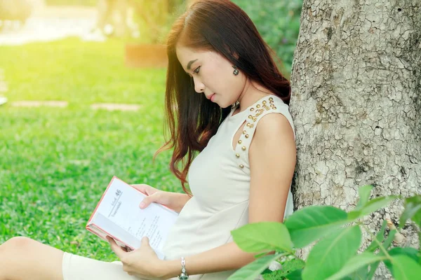 Aziatische vrouw lezen van een boek in de tuin voor ontspanning . — Stockfoto