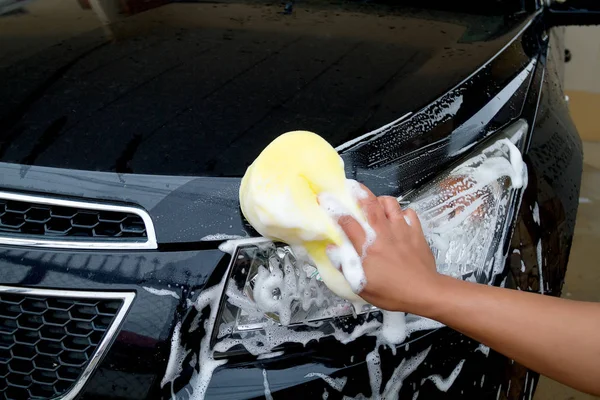 Hand of Man washing the car using the yellow sponge with foam — Stock Photo, Image