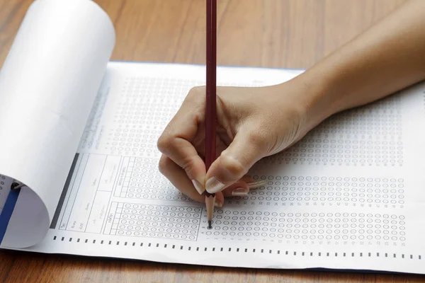 Рука женщины, держащей карандаш на стандартизированной тестовой форме с answ — стоковое фото