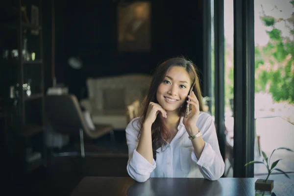 Donna asiatico chiamata con cellulare mentre seduta da solo in c — Foto Stock