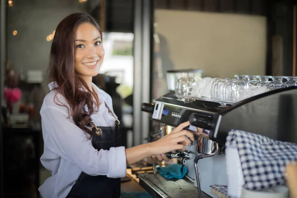 Азіатські жінки Barista посміхається і за допомогою кавомашину в кава — стокове фото