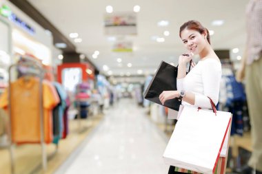 mutluluk, tüketim, satış ve insanlar kavramı - gülümseyen genç kadın alışveriş merkezi/suppermarket arka plan üzerinde alışveriş torbaları ile Asya