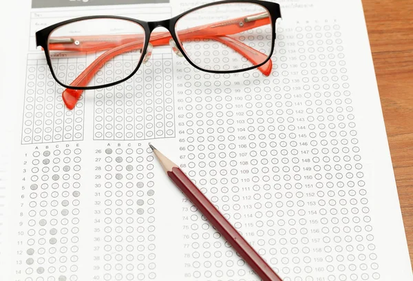 Gafas y lápiz en forma de prueba estandarizada con respuestas burbujeadas en y un lápiz, se centran en anser hoja —  Fotos de Stock