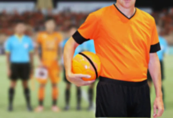 Fotbalový hráč drží míč na fotbalový stadion pozadí — Stock fotografie