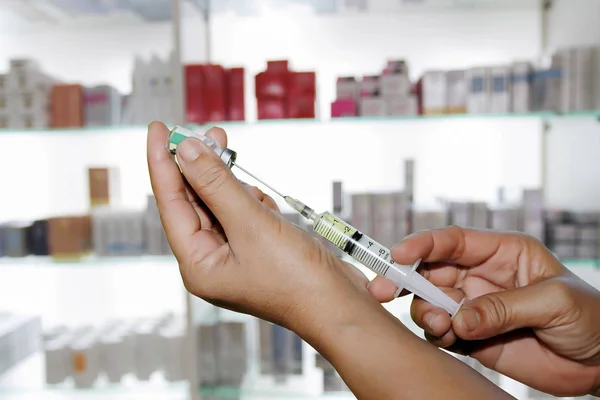 Manos a los médicos llenando una jeringa en la tienda de medicamentos y farmacia — Foto de Stock