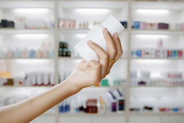 Hand des Arztes hält Medikamentenflasche auf Medizinschrank und s — Stockfoto