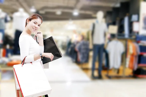 Glück, Konsum, Verkauf und People-Konzept - lächelnde junge Asiatin mit Einkaufstüten über Einkaufszentrum / Suppermarket-Hintergrund — Stockfoto