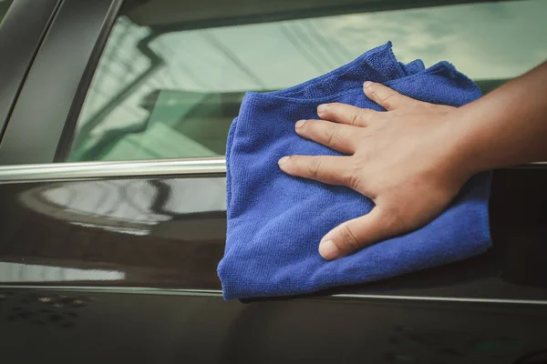 Hand with microfiber cloth cleaning black car. — Stock Photo, Image
