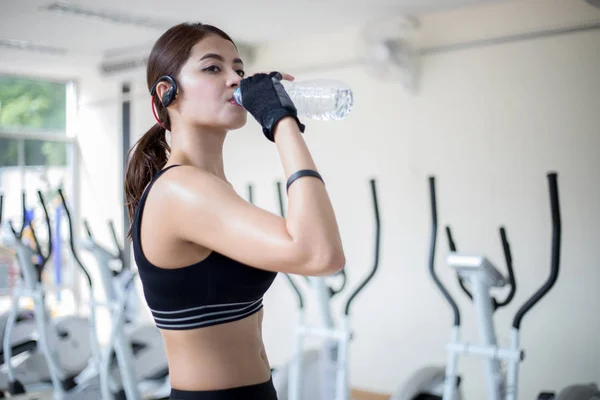 Sporty woman asia drinking water after exercises in the gym. Fit