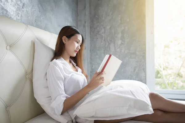 Asiática mujer favorita lectura libro en blanco dormitorio disparo en ma —  Fotos de Stock