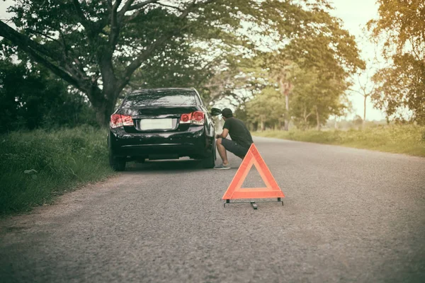 Hombre estresado sentado después de una avería de coche con el triángulo rojo de — Foto de Stock