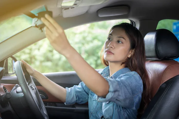 Las mujeres asiáticas están ajustando el espejo retrovisor del coche — Foto de Stock