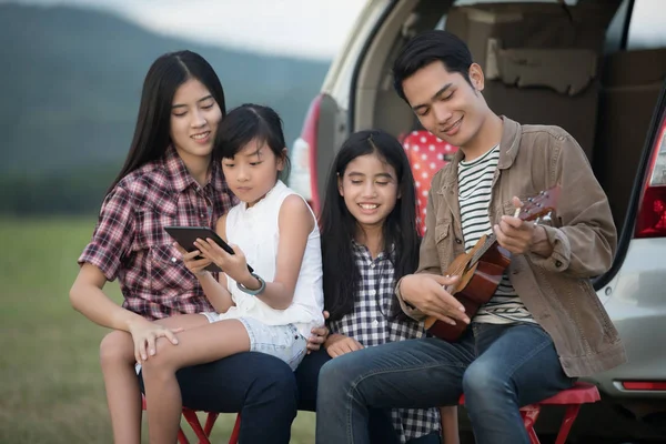 Feliz niña jugando ukelele con asiático familia sentado en t —  Fotos de Stock