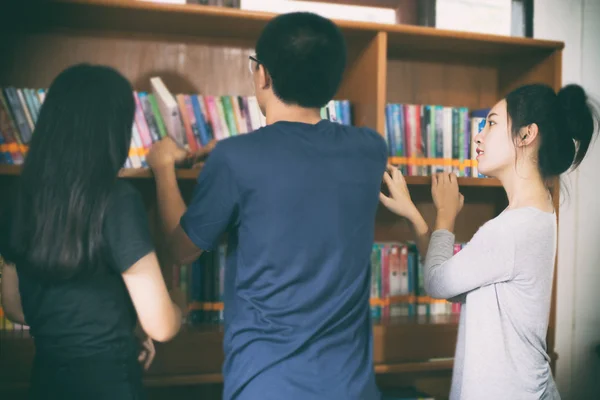 Asiática mujer estudiantes holding para selección libro en biblioteca —  Fotos de Stock