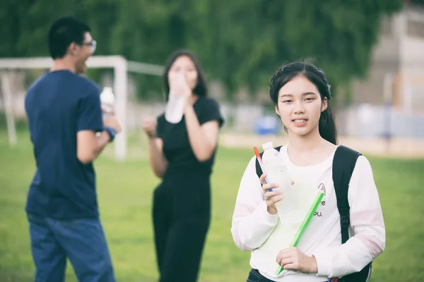 Азиатская группа студентов держит бутылку воды на лужайке кампуса — стоковое фото