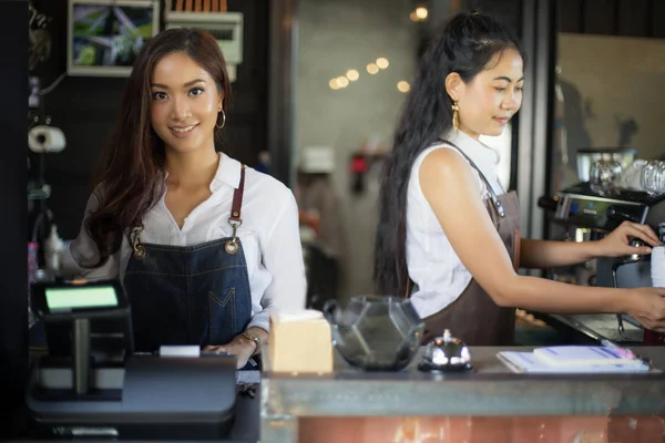 Asyalı kadınlar Barista gülümseyen ve kahve makinesi kahve s kullanma