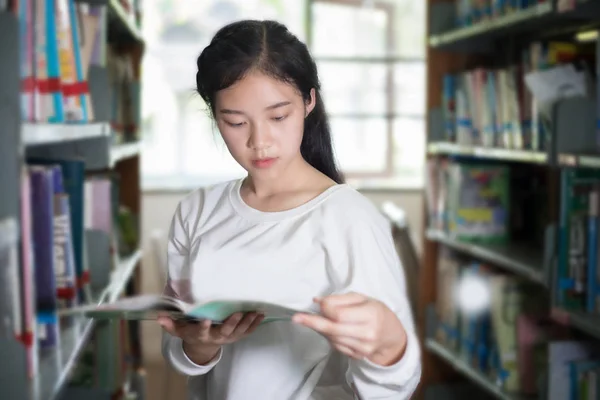 Aziatische vrouwelijke studenten houden voor selectie boeken in bibliotheek — Stockfoto