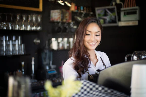 Азіатські жінки Barista посміхається і за допомогою кавомашину в s кави — стокове фото