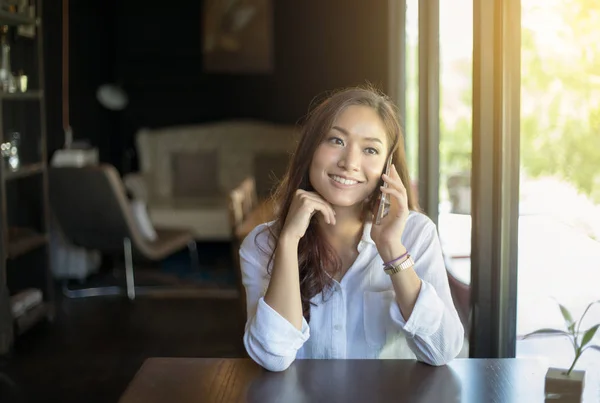 Donna asiatico chiamata con cellulare mentre seduta da solo in c — Foto Stock