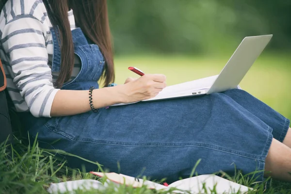 Sonriendo hermosa chica asiática leyendo libro y trabajando en el árbol en —  Fotos de Stock