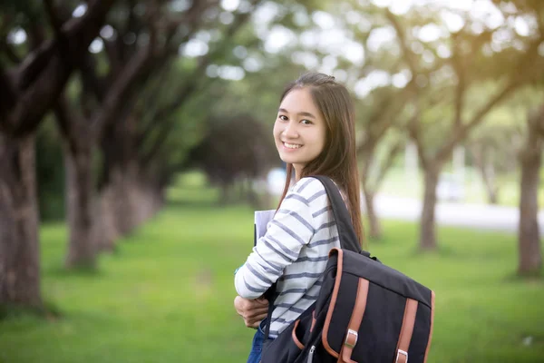 Hermosa chica asiática estudiante sosteniendo libros y sonriendo a la cámara —  Fotos de Stock