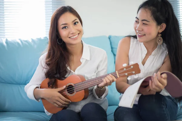 İki Asya kadınlar eğlenceli yaşıyorsanız ukulele oynama ve hom gülümseyen