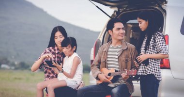 Asya aile t oturmuş ukulele oynamaktan mutlu küçük kız