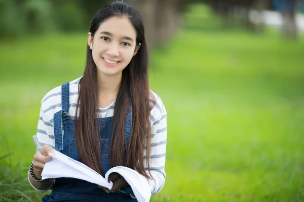 Sonriendo hermosa chica asiática leyendo libro y trabajando en el árbol en —  Fotos de Stock