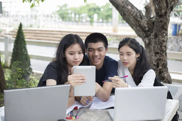 Grupo Asiático de estudiantes que usan tabletas y portátiles compartiendo con t — Foto de Stock