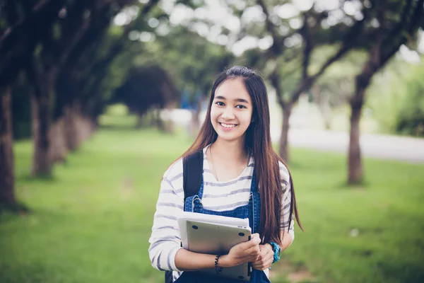 Beautiful Asian girl student holding books and smiling at camera — Stock Photo, Image