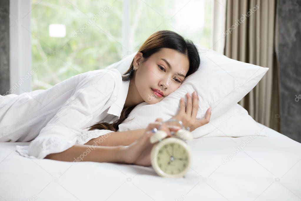 asian woman happy waking up and turning off the alarm clock havi