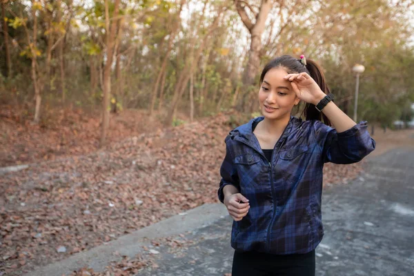 Las mujeres asiáticas están limpiando su sudor mientras trotan afuera en el —  Fotos de Stock