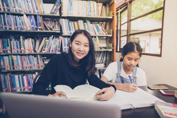 Estudiantes asiáticos leyendo libros en la biblioteca . —  Fotos de Stock