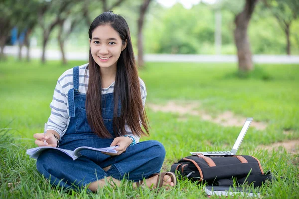 Hermosa chica asiática estudiante sosteniendo libros y sonriendo a la cámara —  Fotos de Stock