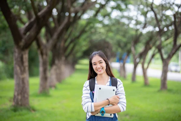 Beautiful Asian girl student holding books and smiling at camera — Stock Photo, Image