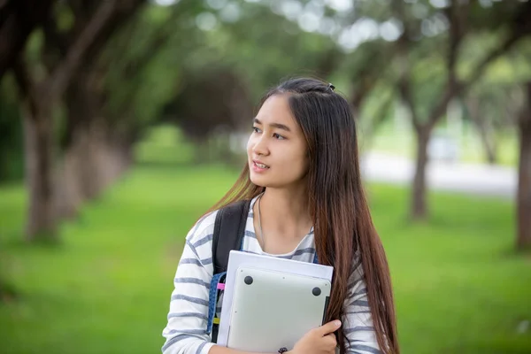 Hermosa chica asiática estudiante sosteniendo libros y sonriendo a la cámara — Foto de Stock