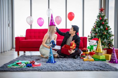 Asyalı çift, içinde Noel hediyesi olan bir hediye kutusu veriyor. 