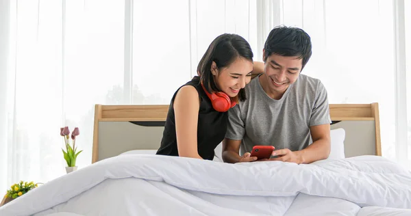 Asiático pareja amantes escuchando música y cantando en su cama un —  Fotos de Stock