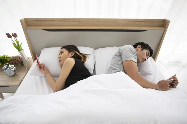 Asiático pareja amantes acostados en su juego de teléfonos móviles en la cama — Foto de Stock