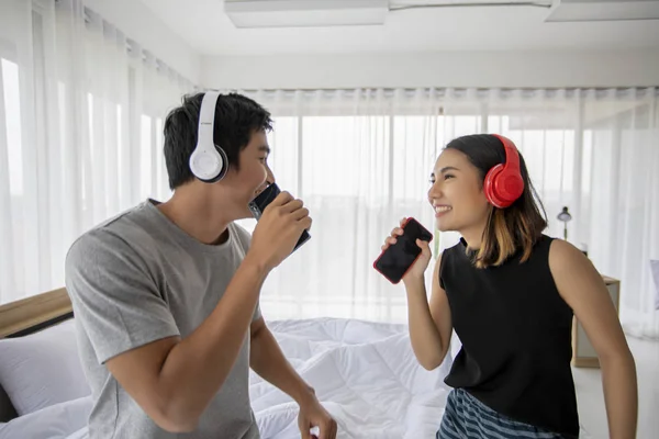 Asian couple lovers listening to music and singing on his bed ro