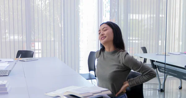 Asiatisk kvinna stretching efter att ha läst boken och arbeta hårt och smil — Stockfoto