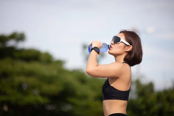 Femme sportive asiatique eau potable en plein air après avoir couru sur sunn — Photo