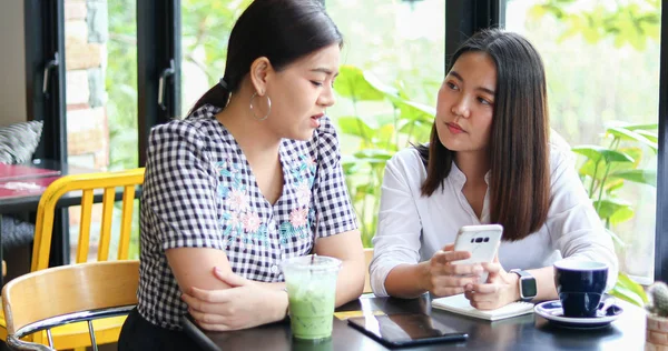 Two Asian women drinking coffee in a cafe and shopping online on — Stock Photo, Image