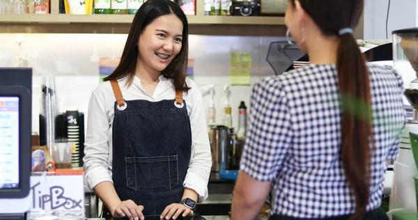 Бариста обслуживает клиентов, а женщина платит за кофе креди — стоковое фото